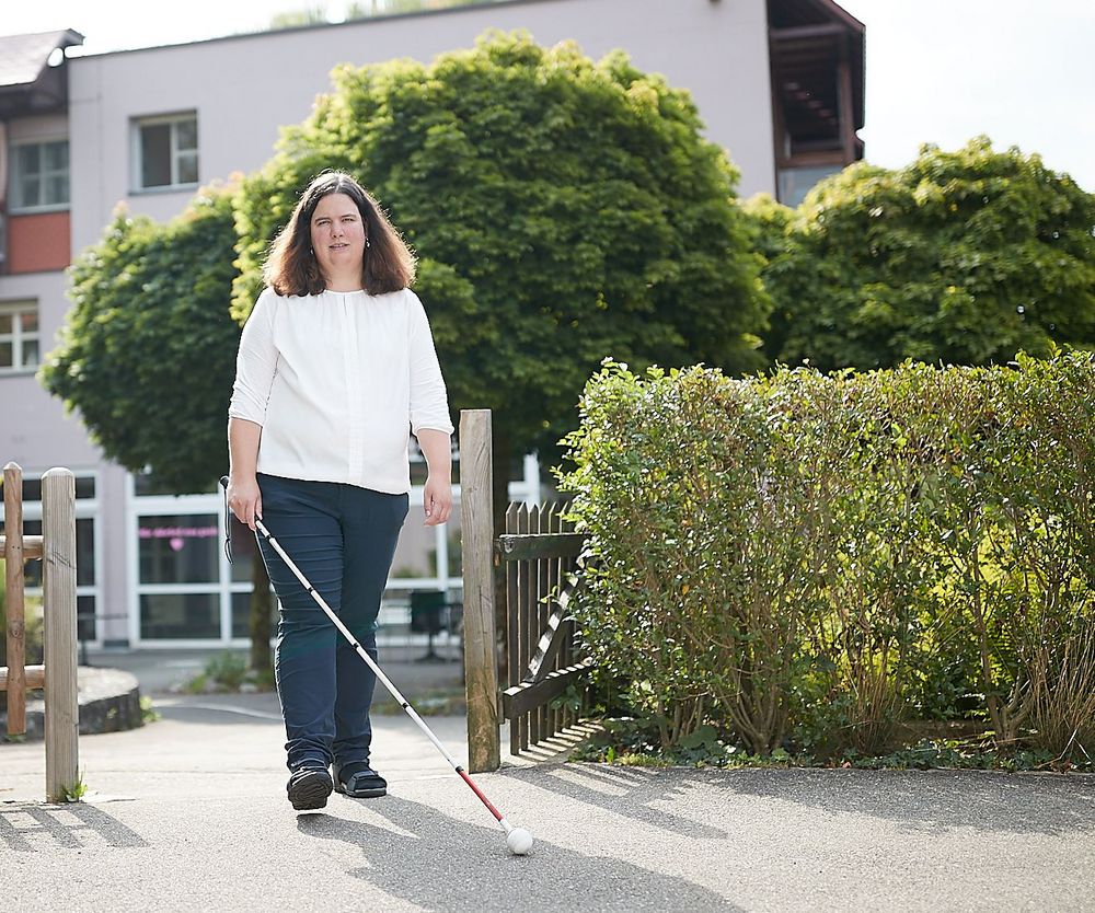 Eine blinde Bewohnerin mit Langstock erkundet den Garten der Mühlehalde. Das fällt ihr leicht, weil sämtliche Bereiche auf sehbehinderte und blinde Menschen ausgerichtet sind.