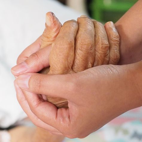 Symbolbild für Palliativ-Versorgung: Eine alte Hand wird liebevoll von einer jungen Hand gehalten.