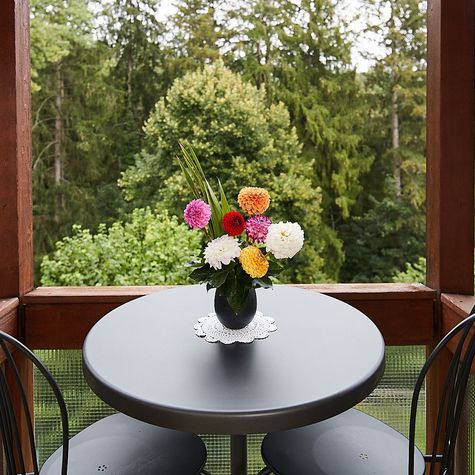 Ein wundervoller Blumenstrauss am Fenster eines Bewohnerzimmers, mit Blick durchs Fenster auf die Bäume der Gartenanlage.